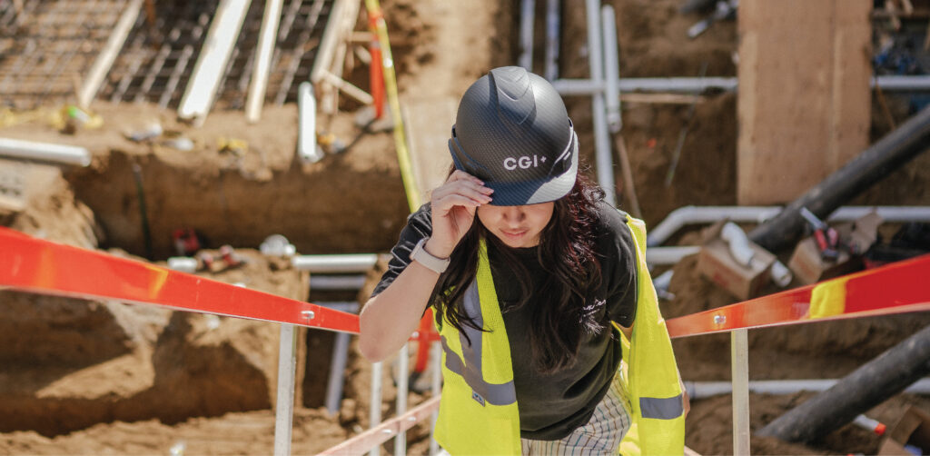 woman walks up construction stairway wearing CGI+ construction helmet