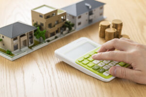 Calculator with three small model buildings and a stack of coins